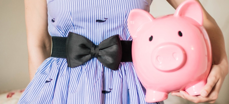 A woman in stripped dress holding a piggy bank