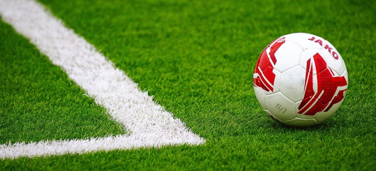 A red and white ball at the corner of a soccer field.