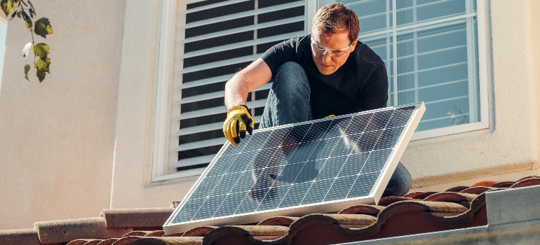 man cleaning solar panels to help with preventing birds from nesting under solar panels