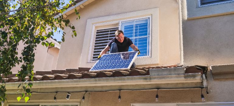 man placing a solar panel on the roof