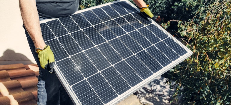 A person holding solar panel as a symbol of how to maintain solar panels in the fall