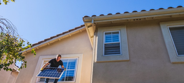 A man on the roof holding solar panel