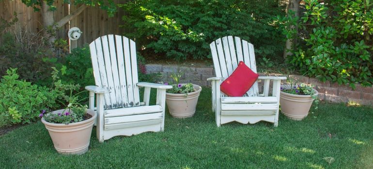 Two white chairs in a backyard.