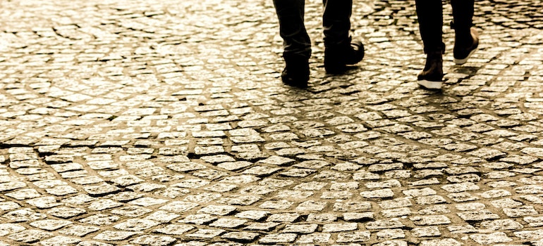 Two people walking on a pavement.