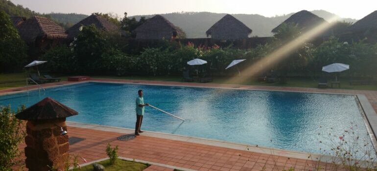 A man cleaning a pool after learning to avoid common pool cleaning mistakes and save money on repairs